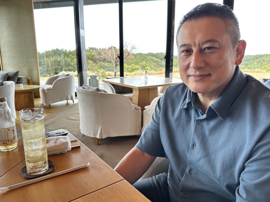 Profile photo of photo embroidery artist DAI HIGUCHI. He is seated in a cafe, looking calm and relaxed.